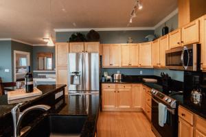 Una cocina con gabinetes de madera y un refrigerador de acero inoxidable. en Fabulous Ocean Views! Miles of Sandy Beach! OurSandCastle, en San Marine