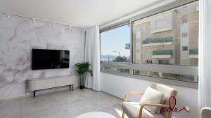 a living room with a tv and a large window at Designer suite in Sea Side complex - By Edomlux in Eilat