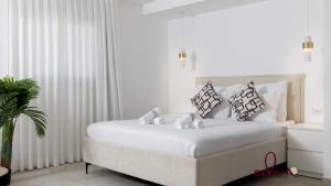 a white bedroom with a bed with white sheets and pillows at Designer suite in Sea Side complex - By Edomlux in Eilat +11 photos