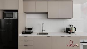 a kitchen with white cabinets and a black refrigerator at Designer suite in Sea Side complex - By Edomlux in Eilat
