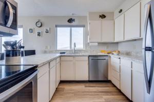 a kitchen with white cabinets and a window at Ocean Front Condo, View of Lighthouse, Nye Beach! Nye Beacon in Newport +22 photos