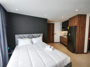 a bedroom with a large white bed and a kitchen at Harmony Coliving Ecuador Pool Carolina Park Quito in Quito