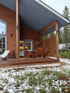a cabin with a deck with chairs and a table at Villa Raanujärvi 