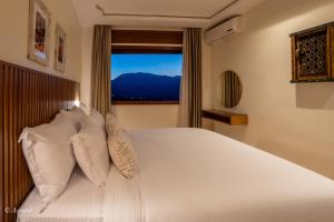 une chambre avec un lit avec des oreillers blancs et une fenêtre dans l'établissement Ain Chaouen, à Chefchaouen