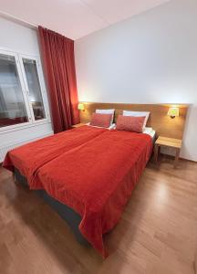 a bedroom with a large bed with a red blanket at Premium Chalet huoneisto kylpylän vieressä in Vierumäki
