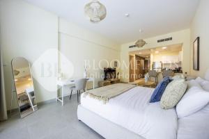 a bedroom with a white bed and a dining room at Bloomfileds Cozy Stu in Park View in Mushayrib