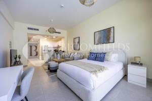 a white bedroom with a white bed and a table at Bloomfileds Cozy Stu in Park View in Mushayrib