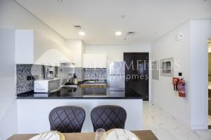 una cucina con due sedie e un bancone di Boomfields Iconic 2Br In The Gate Masdar a Abu Dhabi Intl Altre 10 foto