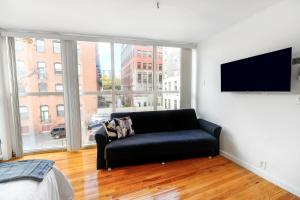a living room with a black couch and a flat screen tv at Modern 3BR Townhouse with Private Rooftop & Parking Minutes to NYC in Hoboken
