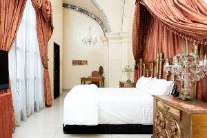 a bedroom with a white bed and red curtains at Ébano by PB - Palacio Borghese in Oaxaca City +26 photos