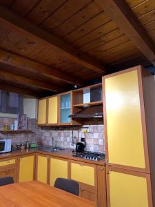 Una cocina con gabinetes amarillos y una mesa de madera. en Living Adua Centro, en Tortona 13 fotos más