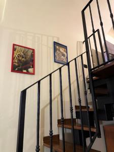 a staircase with black railings and pictures on the wall at Living Adua Centro in Tortona