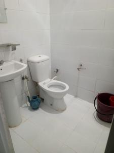 a white bathroom with a toilet and a sink at Grand Arham Hotel Faizabad in Rawalpindi
