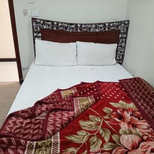 a bed with a red blanket on top of it at Grand Arham Hotel Faizabad in Rawalpindi
