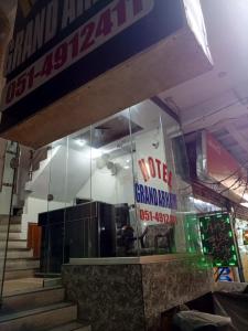 a building with a glass facade with a sign on it at Grand Arham Hotel Faizabad in Rawalpindi