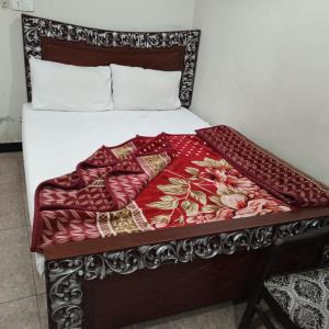 a bed with a wooden headboard with a red blanket at Grand Arham Hotel Faizabad in Rawalpindi