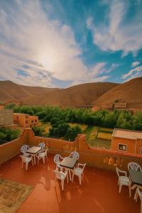 a balcony with tables and chairs and mountains in the background at Auberge la belle vue dades in Akhendachou nʼAït Ouffi