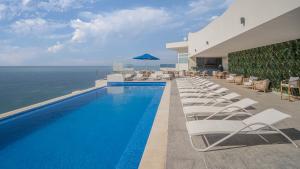 a swimming pool with lounge chairs and the ocean at Encantame Towers Velero 901 in Playa Encanto