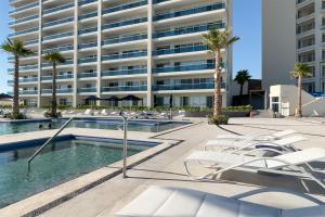 a hotel with a pool and lounge chairs in front of a building at Cozy beach front getaway Encantame Towers E304 in Playa Encanto