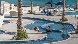 ein Pool mit Palmen und Menschen im Wasser in der Unterkunft Amazing 2 bedroom Beach Front Condominium at Encantame C1102 in Playa Encanto