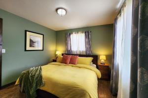 a bedroom with a bed with yellow sheets and red pillows at Ocean View, Walk to Everything! Dog Friendly! Wheelhouse Cottage in Yachats