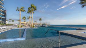 ein Swimmingpool mit Palmen und dem Meer in der Unterkunft New and Amazing 3 bedroom Ground Floor Corner Beach Front Encantame C-101 in Playa Encanto