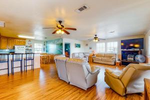 a living room with a ceiling fan and a kitchen at Escape Gulf Views Large Deck Pet Friendly in Crystal Beach