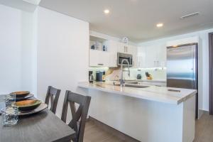 a white kitchen with a table and a refrigerator at Panoramic beach front condo Verano 1703 in Puerto Peñasco