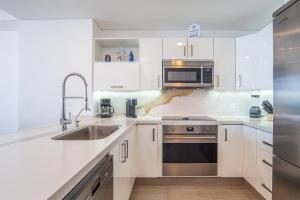 a white kitchen with a sink and a microwave at Panoramic beach front condo Verano 1703 in Puerto Peñasco