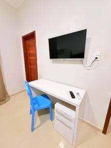 a white desk with a blue chair and a tv on a wall at Nina lar in Boa Vista