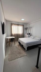 a bedroom with a bed and a desk and a table at West fit 720 in Mossoró