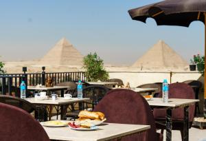 a table with plates of food and the pyramids in the background at Sand pyramids hotel in Giza