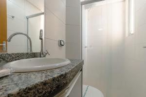 a white bathroom with a sink and a shower at Aproveite este achado! - GC1108 in Maringá +15 photos