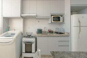 a small kitchen with white cabinets and a microwave at Aproveite este achado! - GC1108 in Maringá
