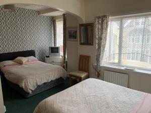 a bedroom with two beds and a tv and a window at Bramleigh Hotel in Blackpool