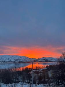 ein Sonnenuntergang über einem Gewässer mit Schnee und Bergen in der Unterkunft Wonderful Seaview Apartment in Tromsø + 25 Fotos