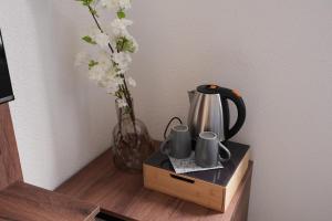 a table with a vase of flowers and a tea kettle at Wohnung IA - Elegante Mini-Suite in Neuwied