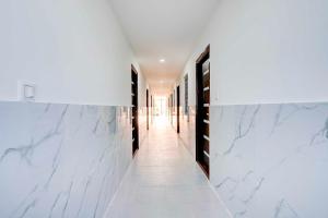 a hallway with white marble walls and a hallway with black doors at Townhouse Bangalore Kundalahalli Metro Station in Bengaluru