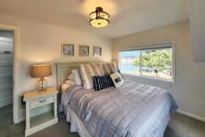 ein Schlafzimmer mit einem Bett mit einer Lampe und einem Fenster in der Unterkunft Alsea Bay Cottage with Hot Tub! The Retreat in Waldport