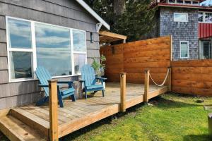zwei Stühle und ein Tisch auf einem Holzdeck in der Unterkunft Alsea Bay Cottage with Hot Tub! The Retreat in Waldport