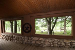 a screened in porch with windows and a stone wall at Jones Riverside Cabin in Utopia