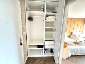 Zimmer mit einem Schrank mit weißen Regalen und einem Bett in der Unterkunft Studio La Petite Oasis - idéal couple - lumineux - calme - 10min à pieds du centre ville & de la plage - balcon exposé sud - 2km du Centre Juno Beach - stationnement & wifi gratuits in Courseulles-sur-Mer