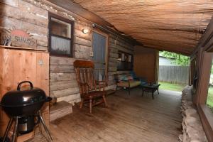 a porch of a log cabin with a stove and a chair at Jones Riverside Cabin in Utopia