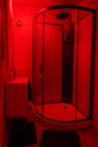 La salle de bains rouge est pourvue d'une douche et d'un lavabo. dans l'établissement Le Baiser 1 le bunker réaménagé en plaisir interdit, au Havre