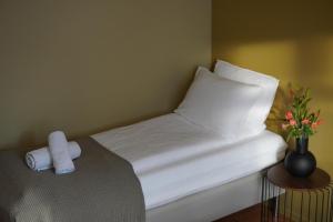 a white bed with a pillow and a vase with flowers at A Place To Stay Stavanger, apartment 5 - free parking- in Stavanger