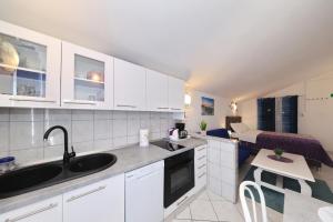 a kitchen with white cabinets and a living room at Apartments Miljenka in Nin