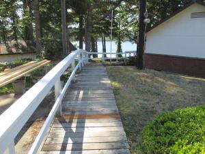Woahink Lake Suites في Dunes City: ممشى خشبي يؤدي إلى منزل به سور