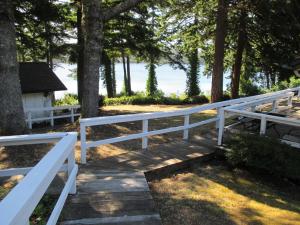 Woahink Lake Suites في Dunes City: سور أبيض بجانب ممشى خشبي