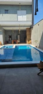 a large blue swimming pool in front of a house at Pousada Coisa Nossa in Itanhaém