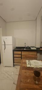 a kitchen with a white refrigerator and a counter at Pousada Coisa Nossa in Itanhaém